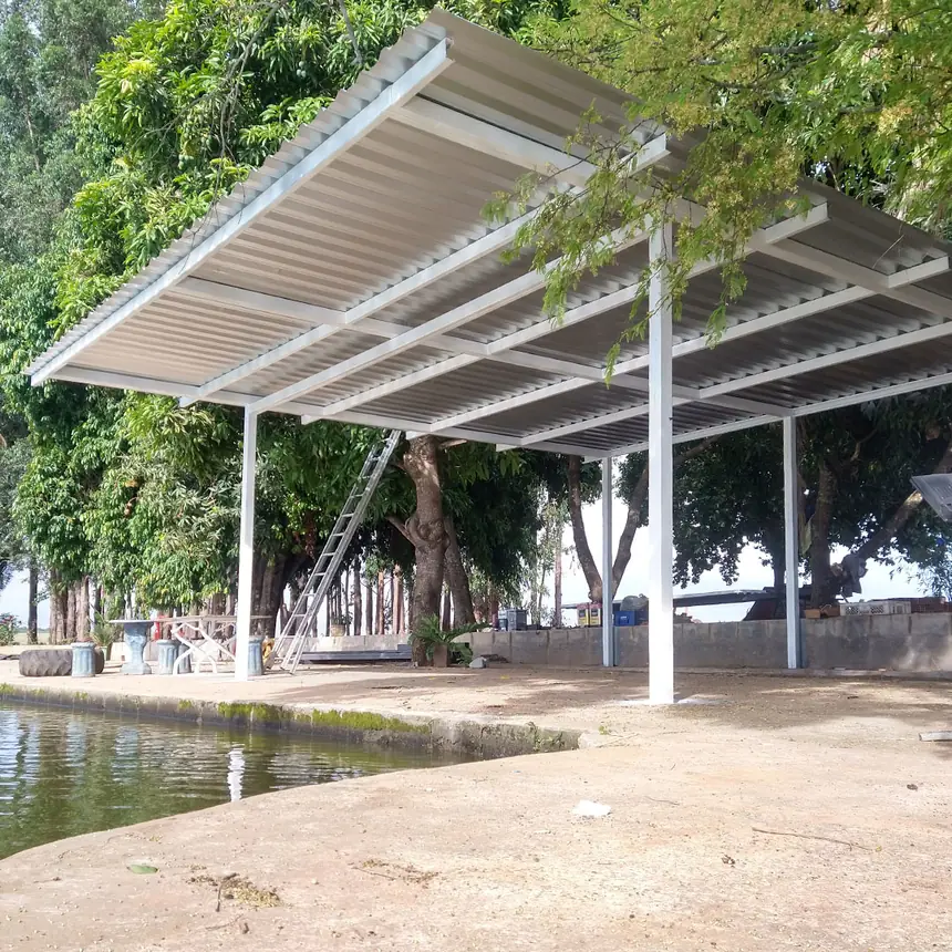 Cobertura metálica ampla sobre área de lazer à beira da água